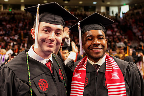 Two students posing in caps and gown at commencement.