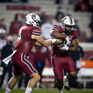 A quarterback hands off the ball to a running back in 2020 Gamecock football action. 